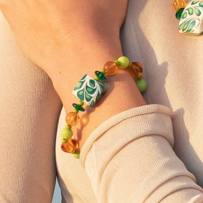 Model wearing MURRINAMURANO Venezia Bracelet from the Coral Bay Collection, handcrafted in Original Murano glass, 18KT Gold Finish or Rhodium finish, over Brass. Made in Italy – murrinamurano.us