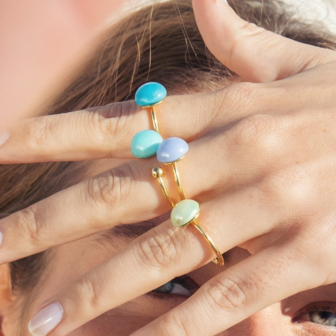 Model wearing MURRINAMURANO Venezia rings from the Seaside Serenity Collection, handcrafted in Original Murano glass, 18KT Gold Finish or Rhodium finish, over Brass. Made in Italy – murrinamurano.us