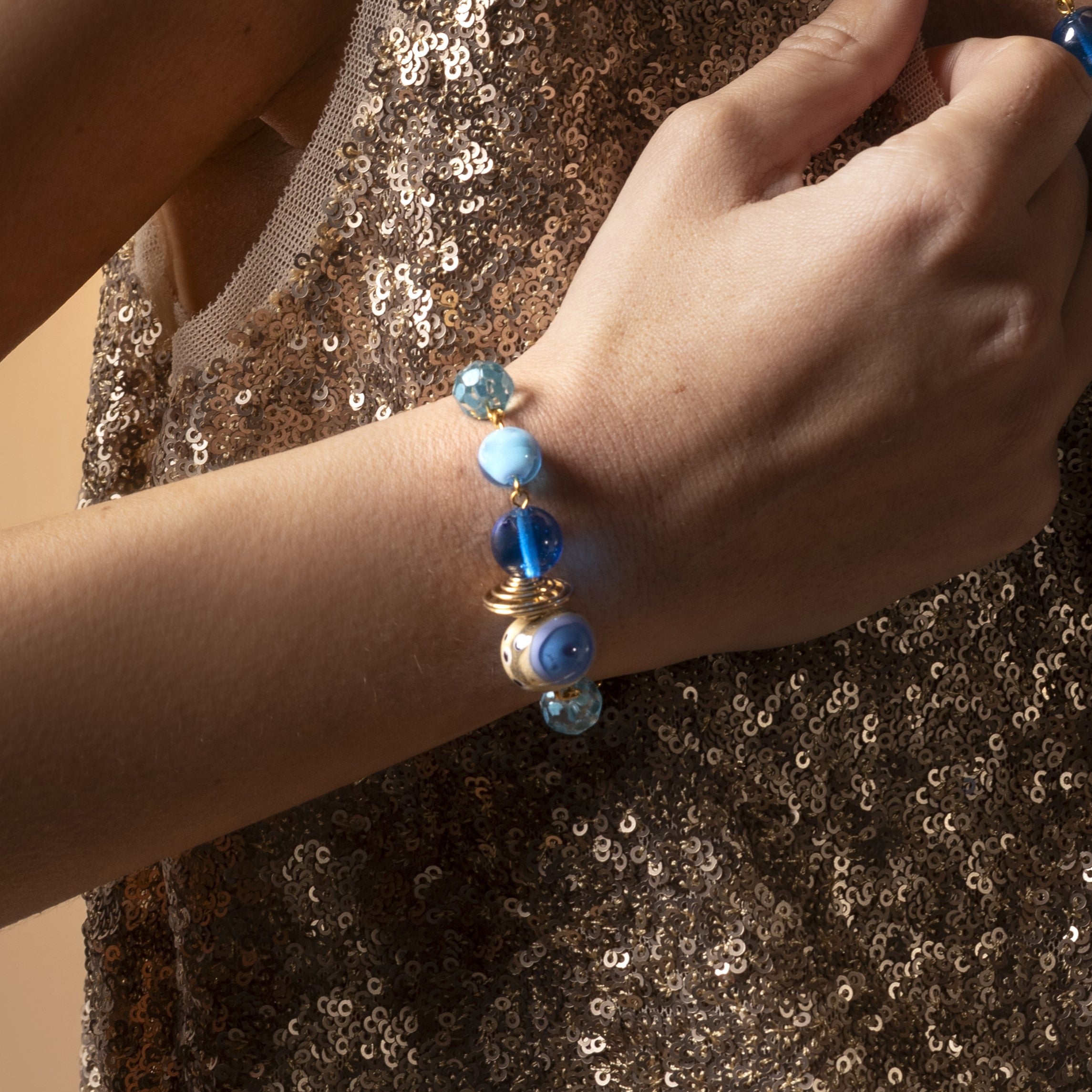 Close-up of a hand wearing a Glow Murano glass bracelet with 18KT Gold Finish over brass, adjustable 7 inches plus extension, handcrafted in Venice, Italy.