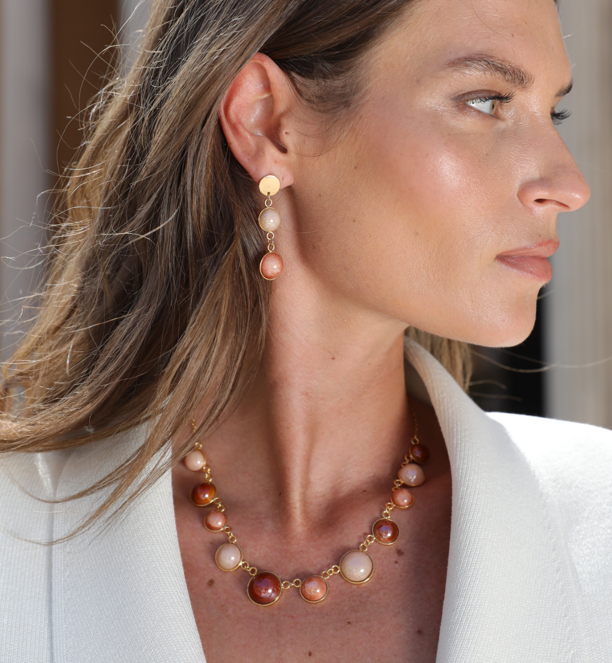 Model wearing MURRINAMURANO Venezia Necklace and Earrings from the Audrey Collection, handcrafted in Original Murano glass, 18KT Gold Finish or Rhodium finish, over Brass. Made in Italy – murrinamurano.us