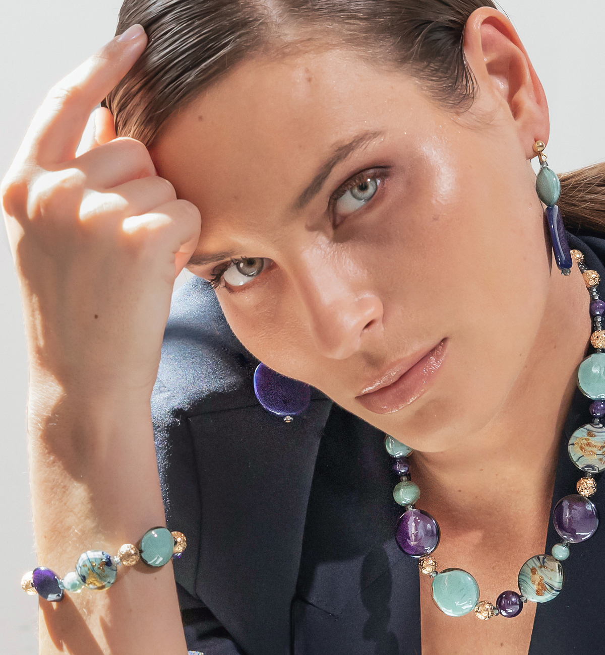 Model wearing MURRINAMURANO Venezia Necklace, Bracelet and earrings from the Gaia  Collection, handcrafted in Original Murano glass, 18KT Gold Finish or Rhodium finish, over Brass. Made in Italy – murrinamurano.us