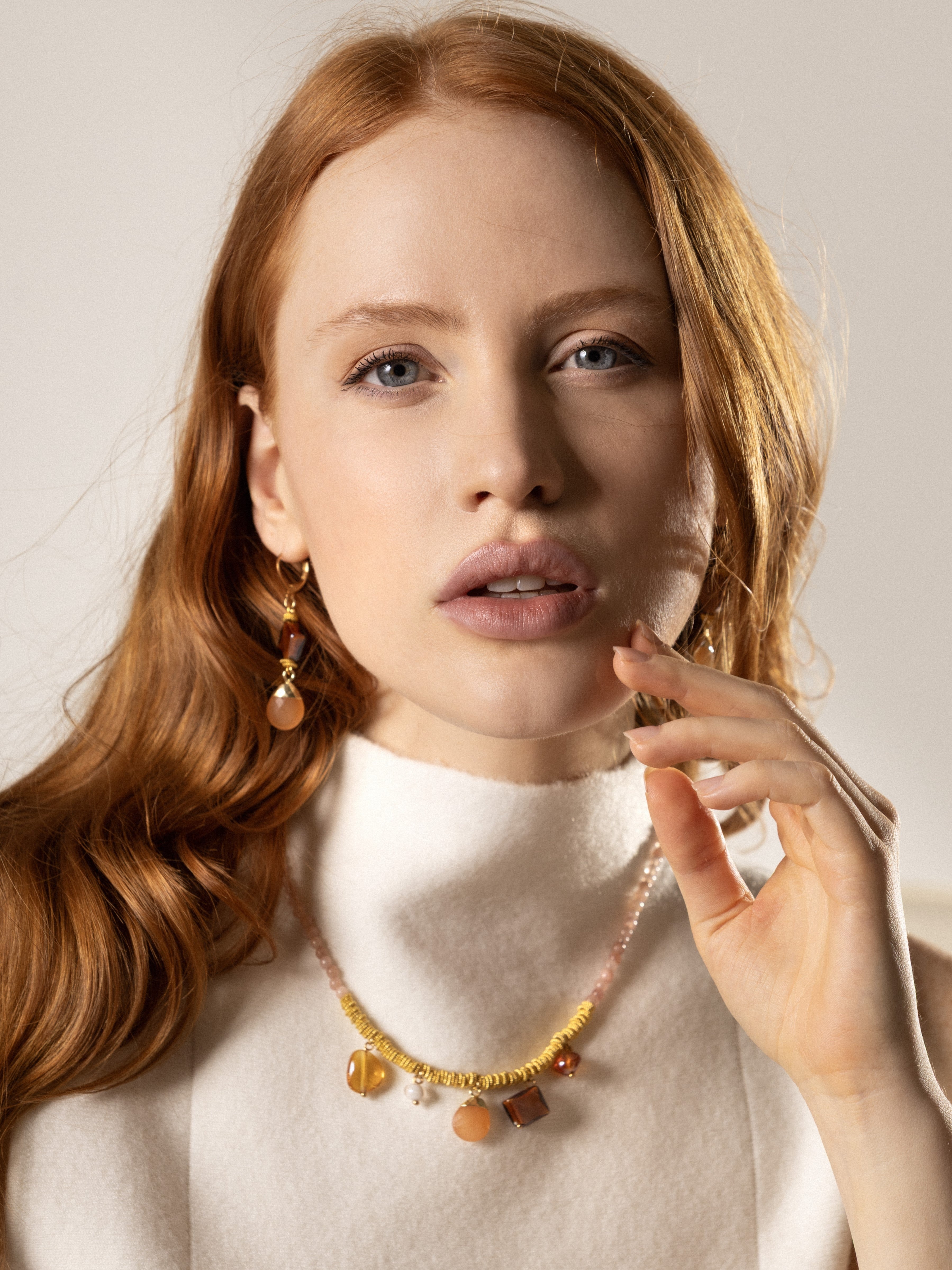 MurrinaMurano.us model wearing Veil Murano glass drop earrings in orange, featuring geometric orange Murano glass beads paired with faceted peach natural stone drops and 18KT gold-plated brass detailing. 