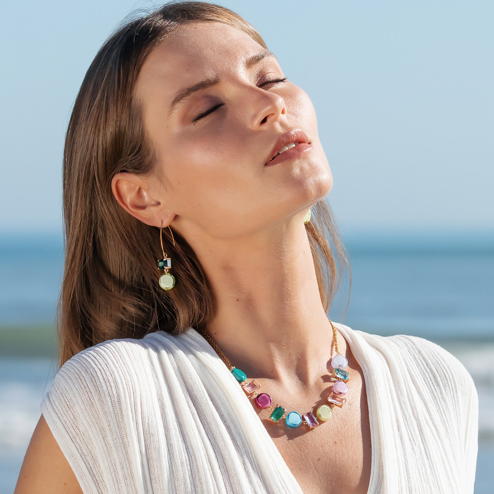 Model wearing MURRINAMURANO Venezia Necklace and Earrings from the Sunset Mirage  Collection, handcrafted in Original Murano glass, 18KT Gold Finish or Rhodium finish, over Brass. Made in Italy – murrinamurano.us