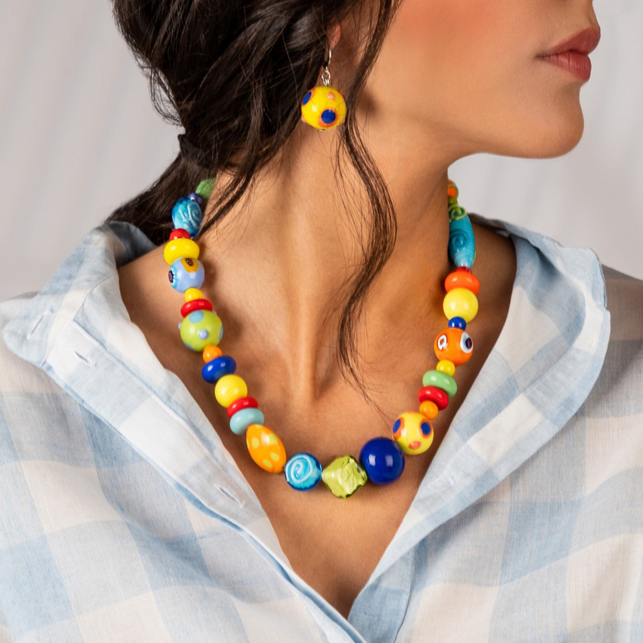 Model wearing MURRINAMURANO Venezia Necklace from the CARIOCA Collection, handcrafted in Original Murano glass, 18KT Gold Finish or Rhodium finish, over Brass. Made in Italy – murrinamurano.us