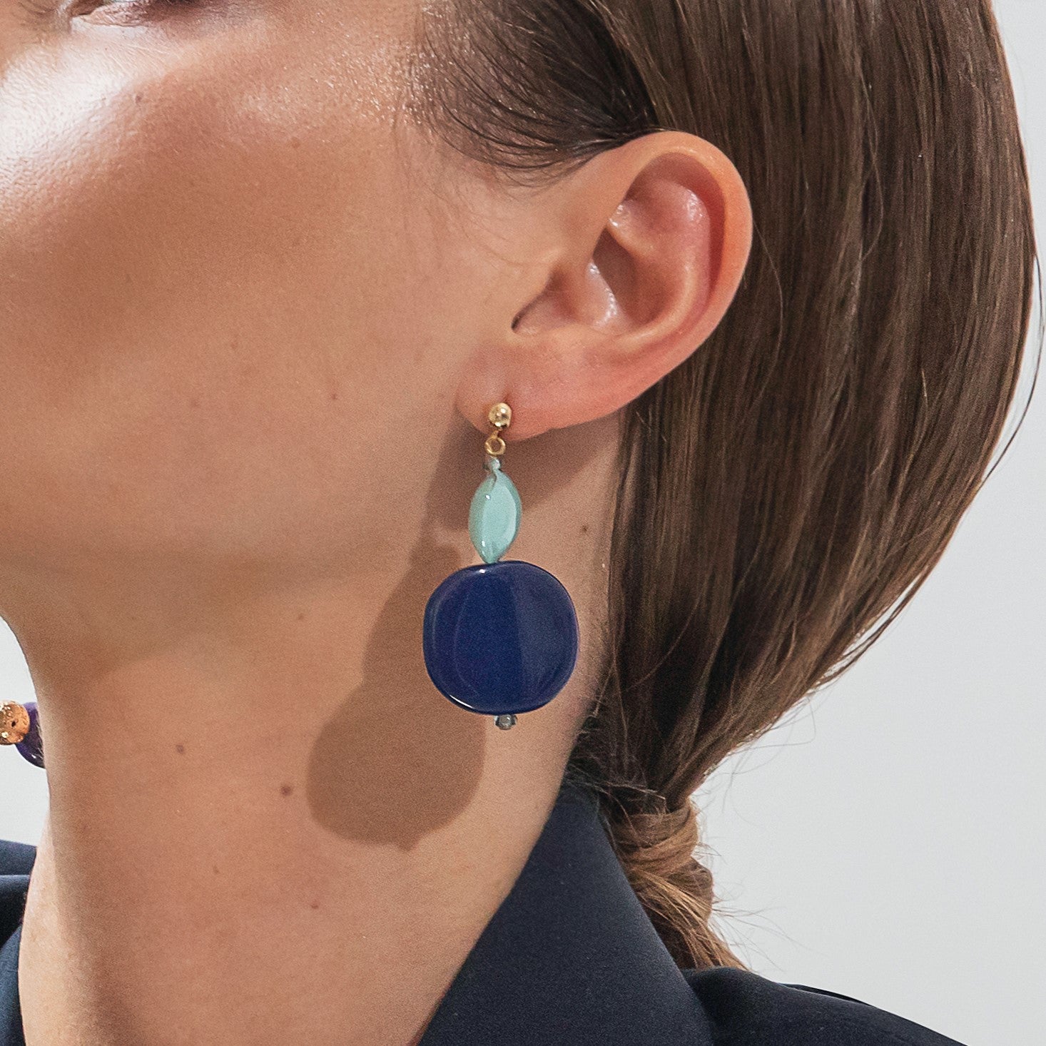 Model wearing MURRINAMURANO Venezia earrings from the Gaia Collection, handcrafted in Original Murano glass, 18KT Gold Finish or Rhodium finish, over Brass. Made in Italy – murrinamurano.us