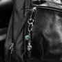 Dusk Collection men’s keychain with lava stone bead, stainless steel hardware and brass accent, 13 cm length, skull detail. attached to a black leather bag