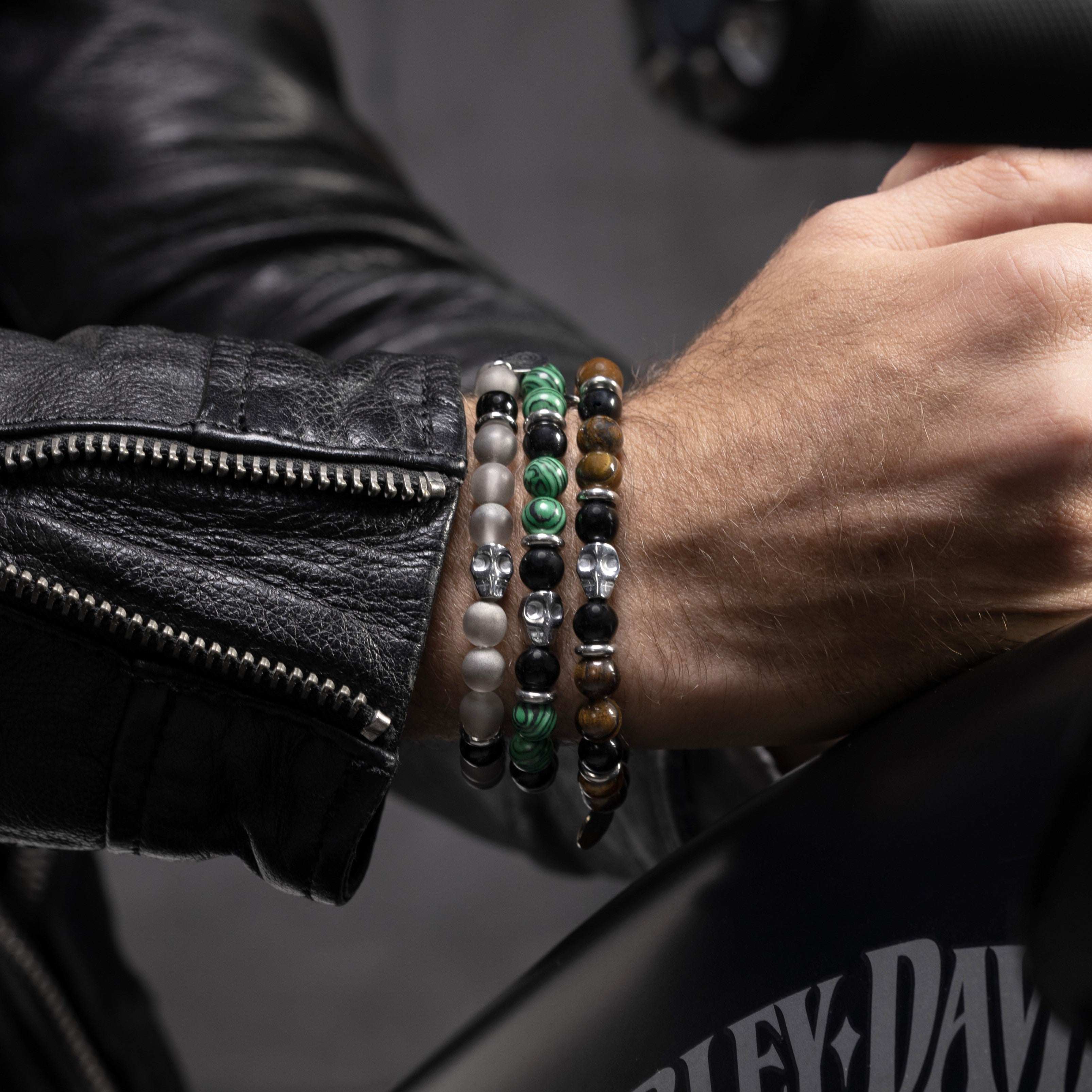 Close-up of a person's wrist wearing Batista men’s bracelet with tiger eye, malachite and glass beads, rhodium finish over stainless steel and brass, adjustable stretch fit, contemporary Italian design.