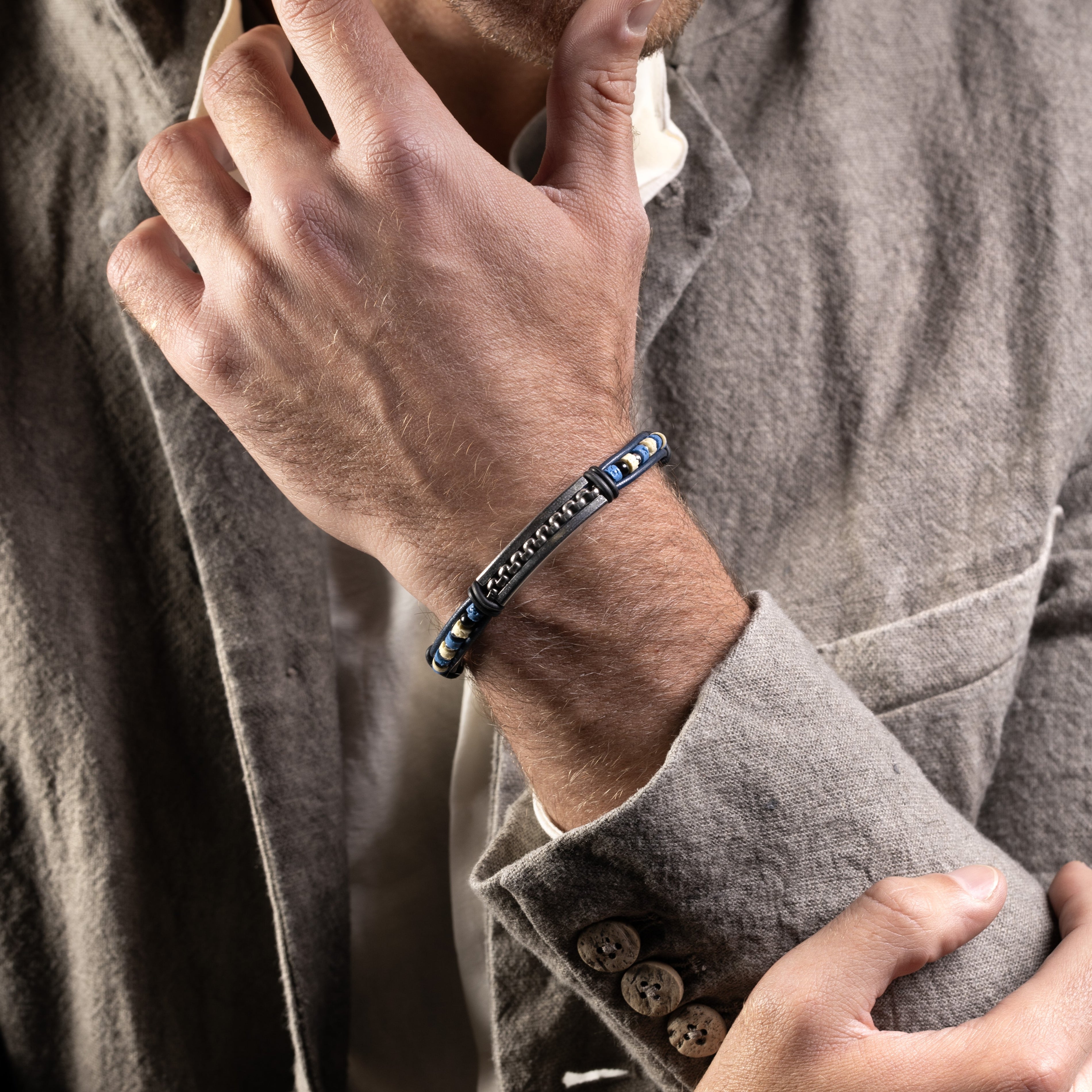 Close-up of a person wearing a Brick men’s bracelet with leather, lava stone and silicone, rhodium finish over stainless steel, 20 cm length, contemporary Italian design.