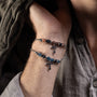 Close-up of a wrist wearing two Stain men's steel and agate bracelets with cross designs.