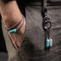 Tag Collection - Murano Glass - Close-up of a keychain with turquoise and gray charms on a person's pocket.