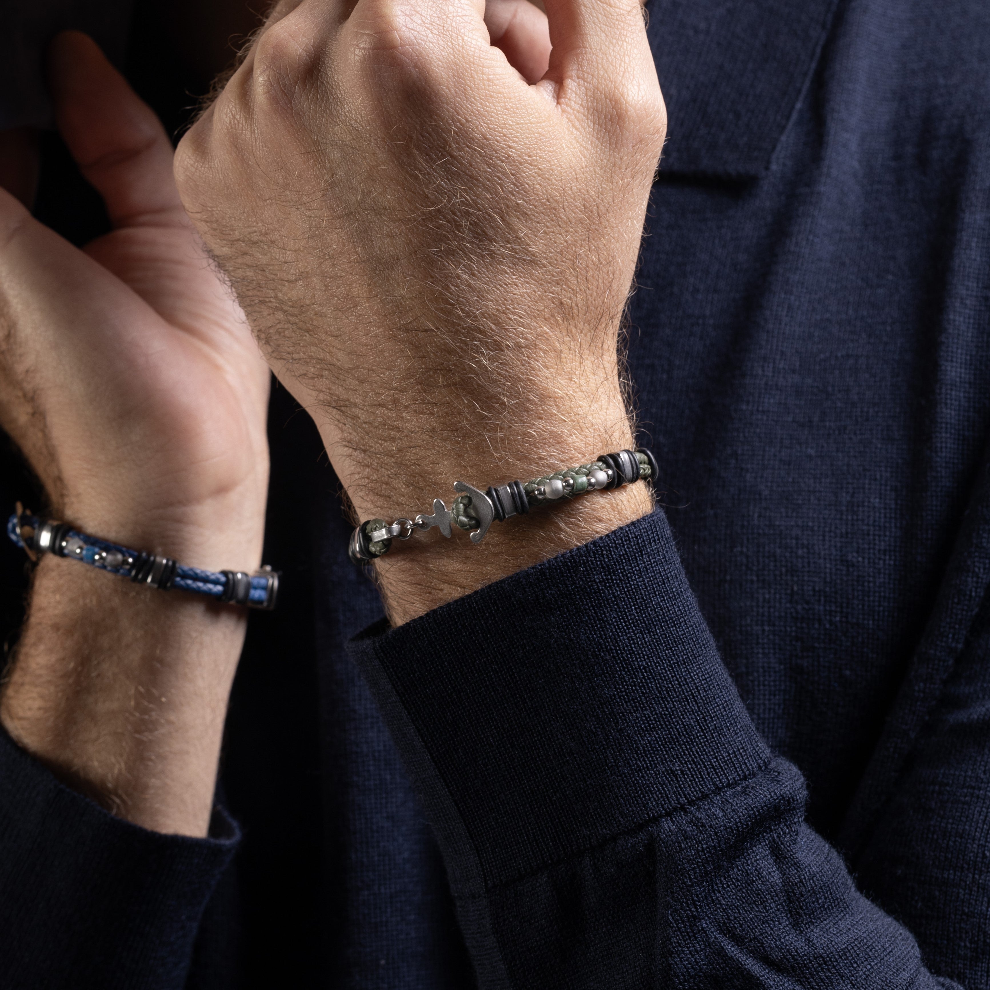 Close-up of a person wearing two Drift Collection men's bracelet with braided leather, stainless steel anchor detail and silicone accents, 21 cm length, contemporary Italian men's jewelry.