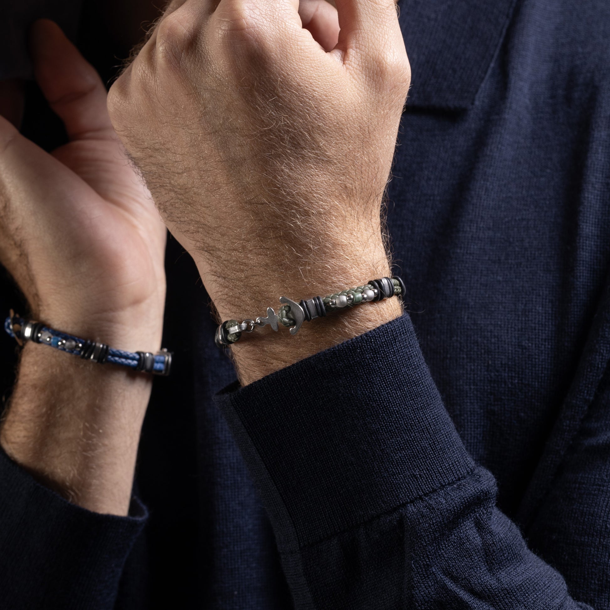 Close-up of a person wearing two Drift Collection men's bracelet with braided leather, stainless steel anchor detail and silicone accents, 21 cm length, contemporary Italian men's jewelry.