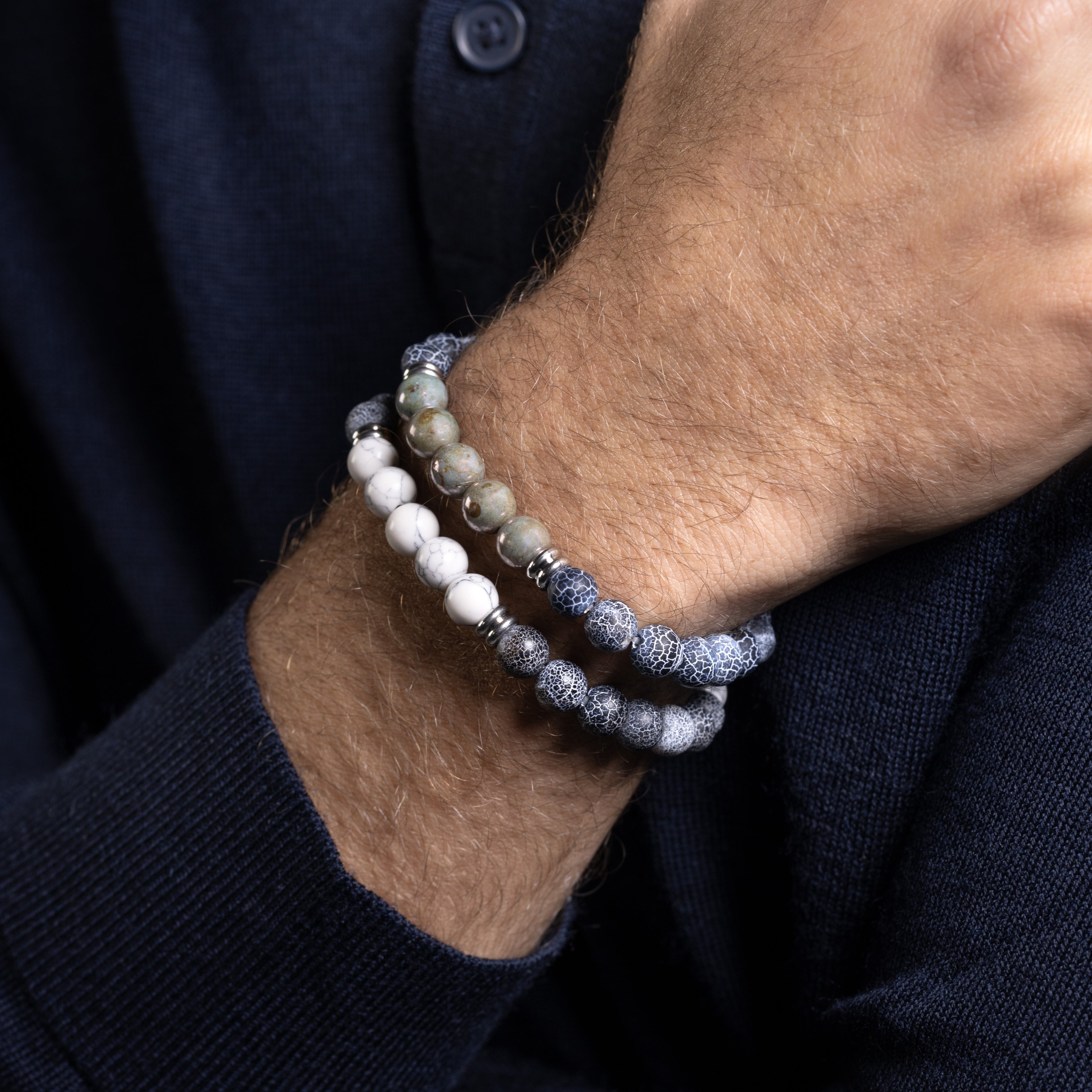 Close-up of a wrist wearing Etna Collection men’s bracelet with lava stone and agate beads, stainless steel and brass accents, adjustable fit, contemporary Italian design. 