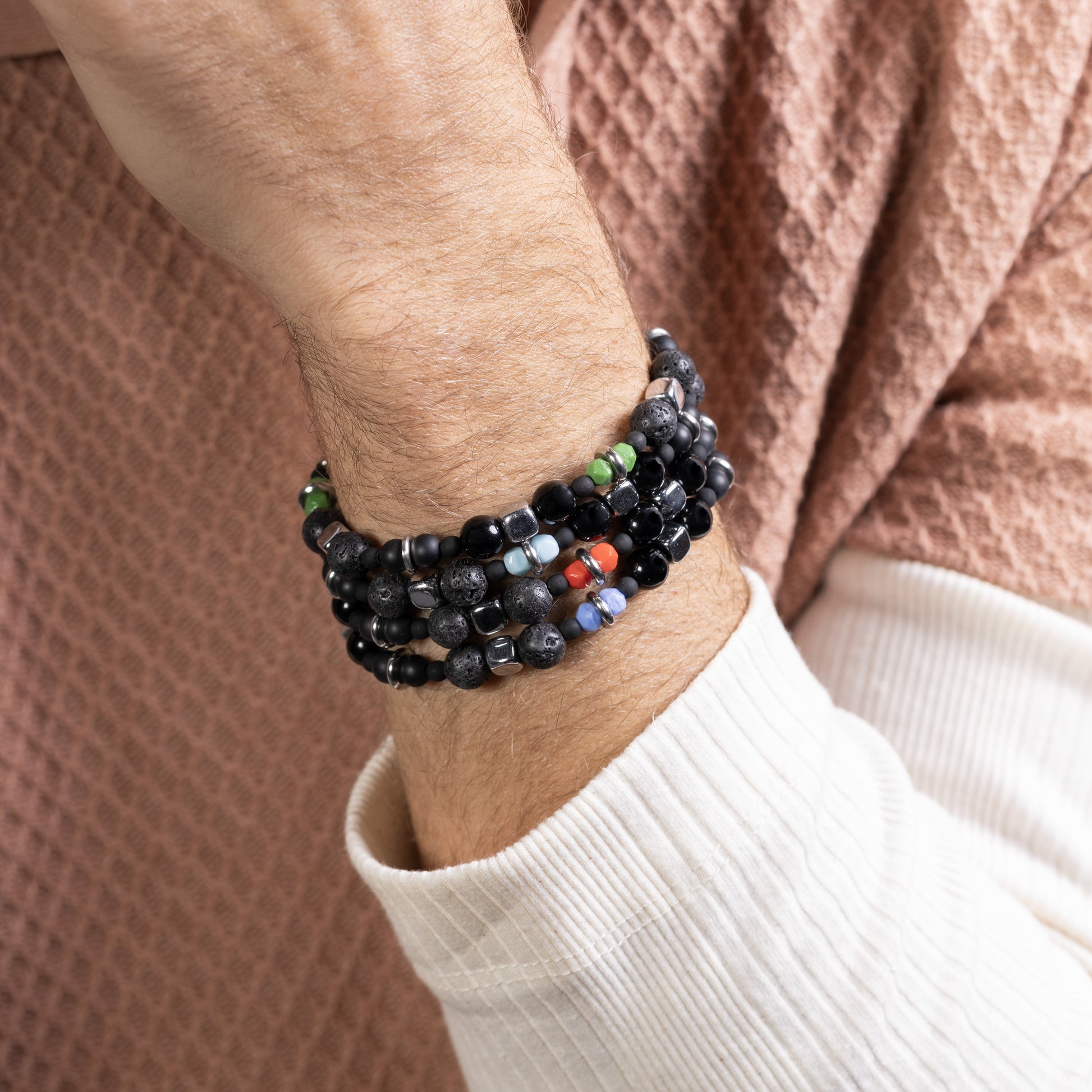 Person wearing a stack of Borghese men’s bracelet with hematite and lava stone, rhodium finish over stainless steel and brass, 20 cm length, contemporary Italian design.