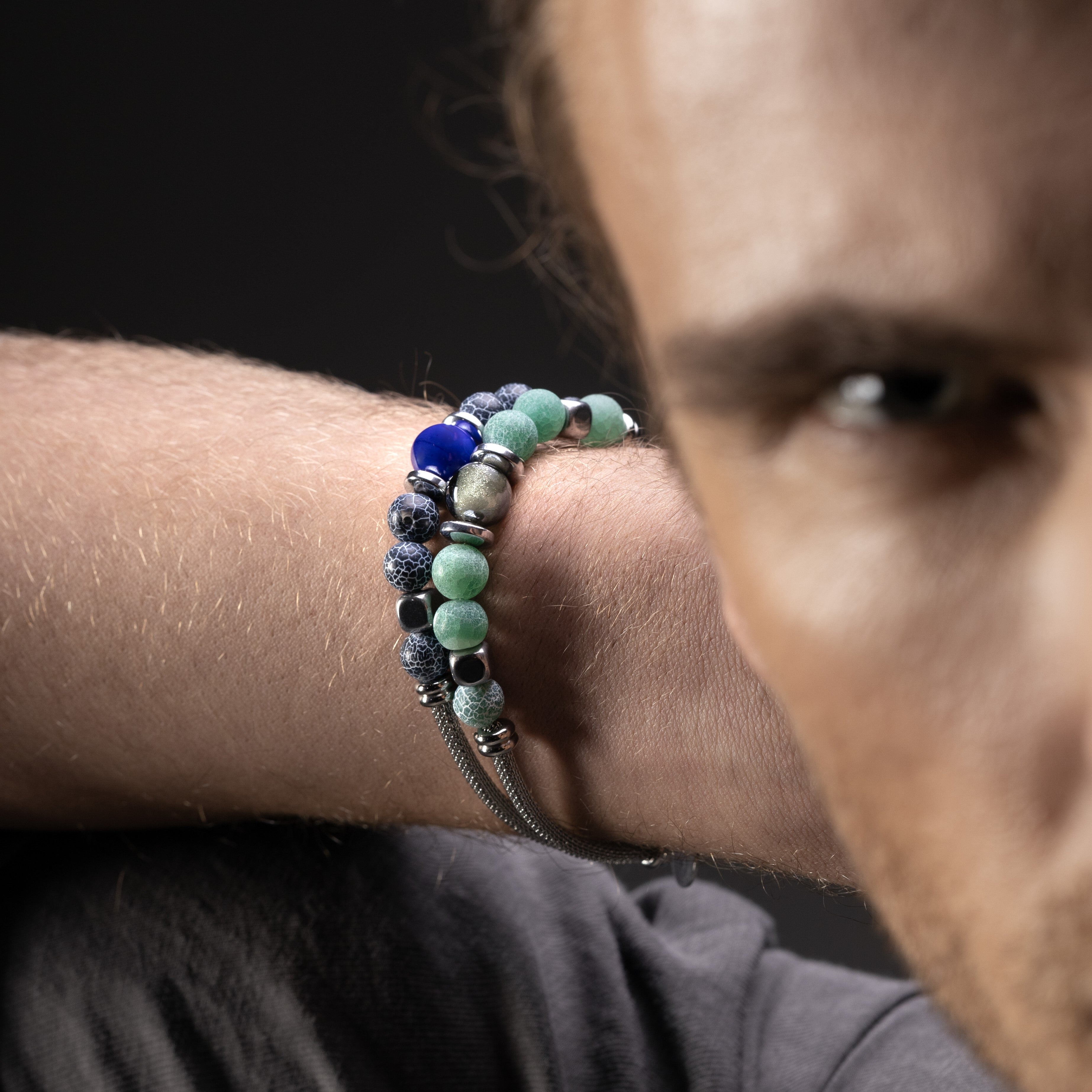 Close-up of a person wearing a Diamante Collection men's bracelet with Agate, Hematite, stainless steel mesh and silicone support, 20 cm length, contemporary Italian design.