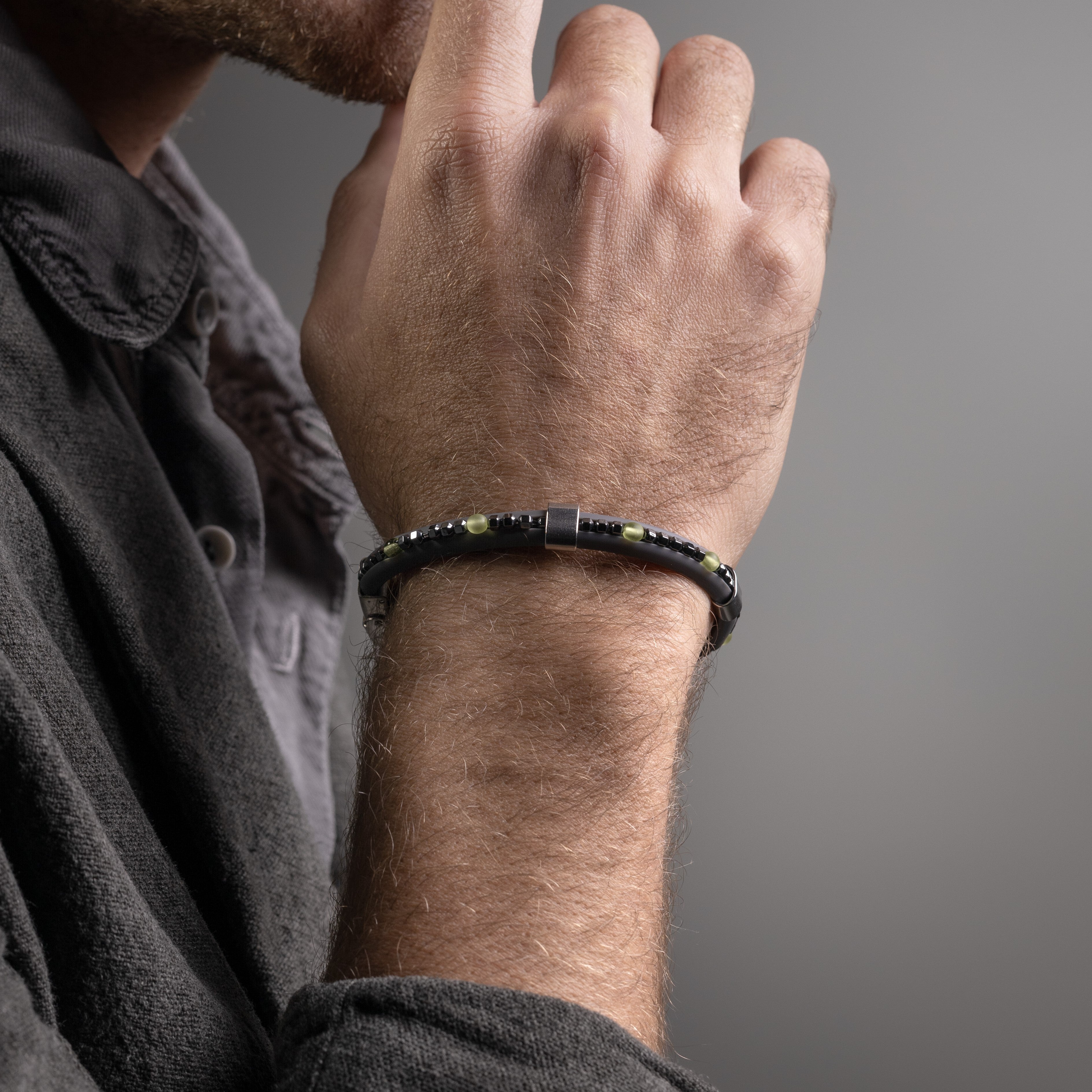 Close-up of a man's wrist wearing a Blast men’s bracelet with Murano Glass , rubber and hematite stones, rhodium finish over stainless steel, 21 cm length, contemporary Italian design.