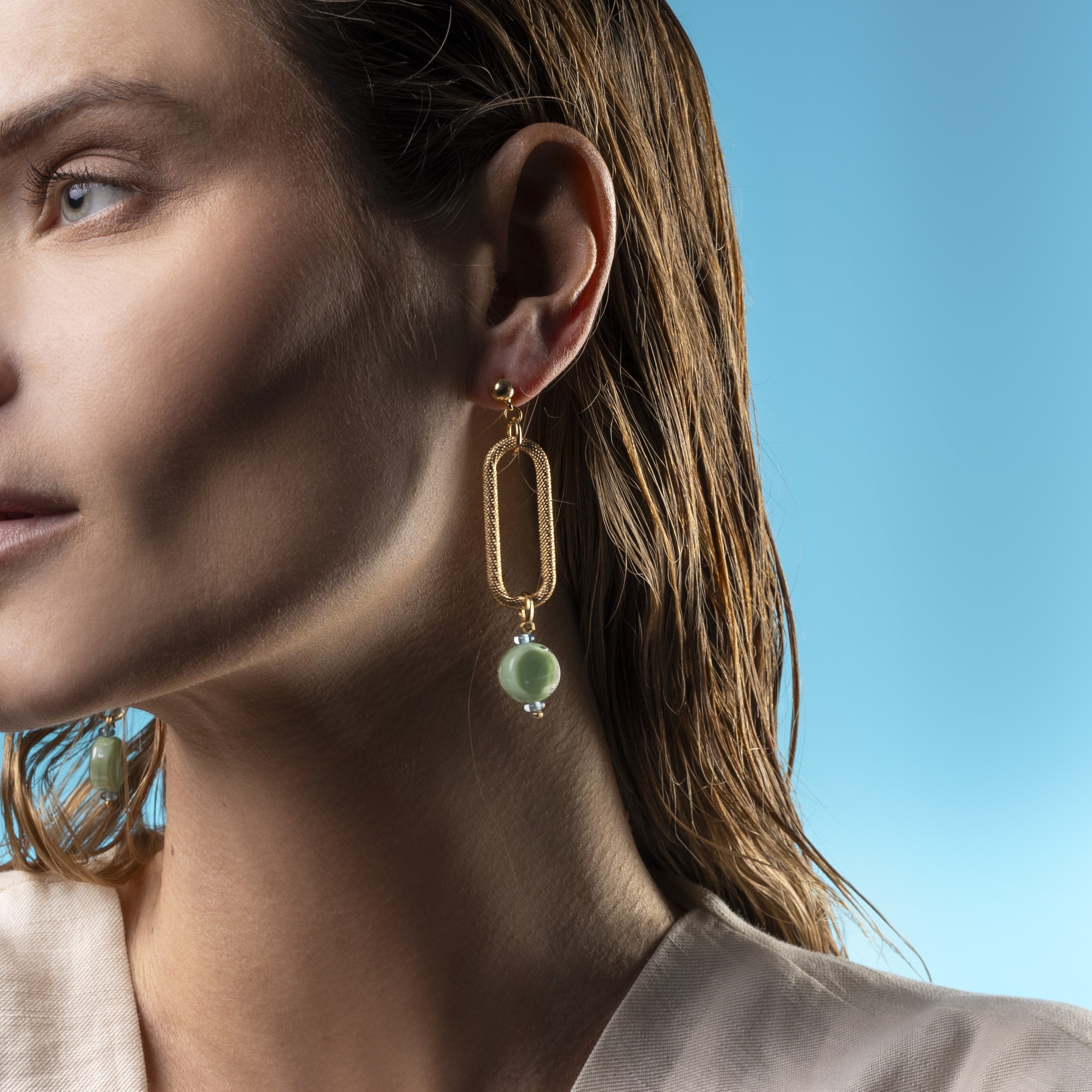 Close-up of a woman wearing Breeze Murano glass link drop earrings with 18KT Gold Finish over brass, handcrafted in Venice, Italy.