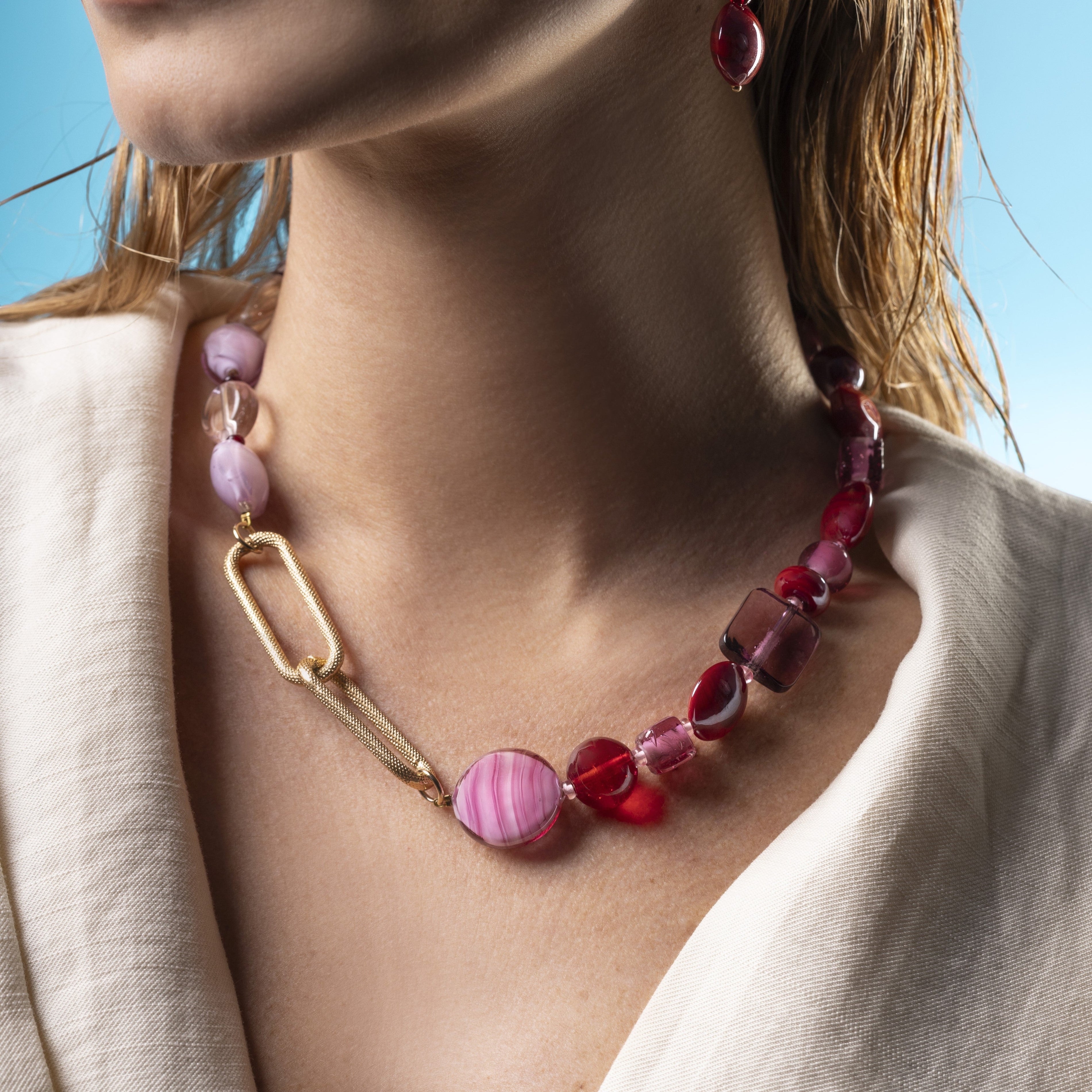 Breeze Murano glass necklace with 18KT Gold Finish over brass, adjustable 18.5 inches with extension, handcrafted in Venice, Italy. worn by a person against a blue sky.