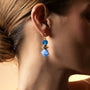 Close-up of a woman wearing a Glow Murano glass drop earrings with 18KT Gold Finish over brass, handcrafted in Venice, Italy, 2 inches length.
