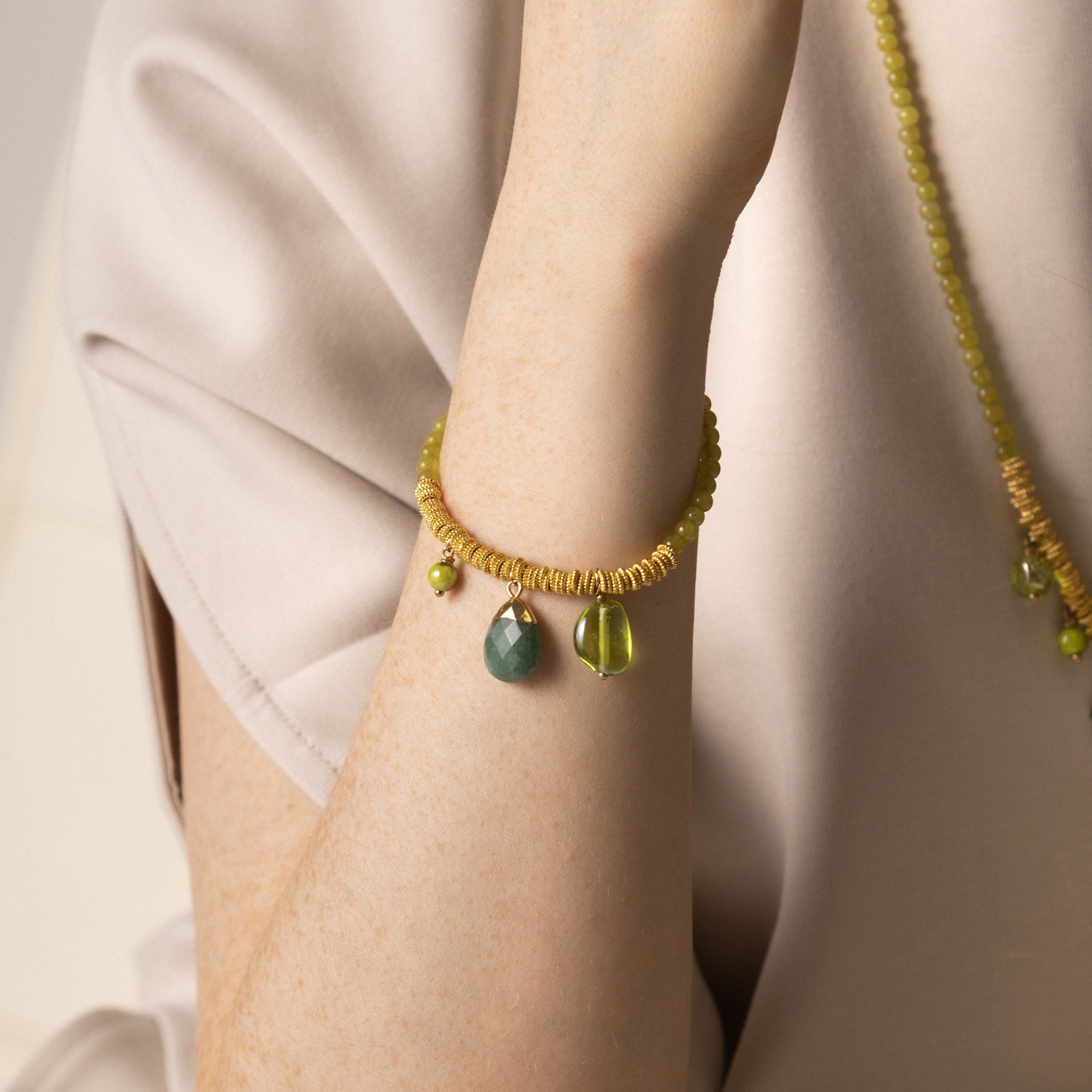 MurrinaMurano.us green Veil Bracelet with Murano Glass beads, glass pendants, and 18KT gold-finished details, shown worn on the wrist. Handcrafted in Italy.