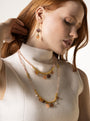 Veil Long Necklace with pale pink Murano Glass beads, 18K Gold-finished metal details, and hard stone accents worn with a cream outfit.
