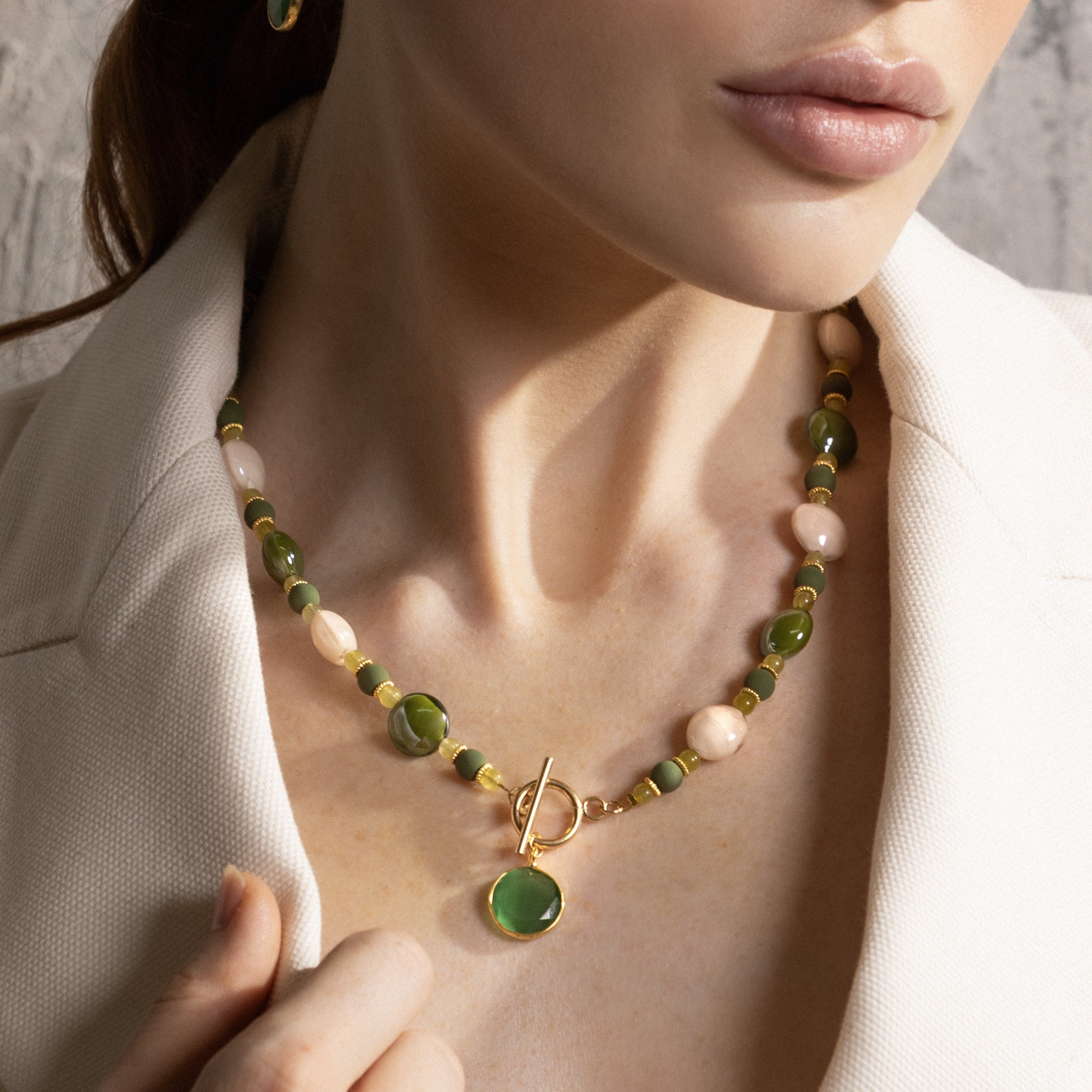 Close-up of the MurrinaMurano.us Trace Choker Necklace in green, featuring rounded Murano Glass beads, pale stone accents, gold spacer details, and a circular toggle clasp with pendant. Handcrafted in Italy.