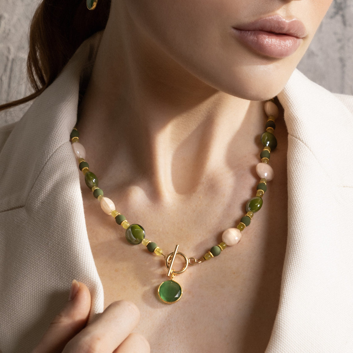 Close-up of the MurrinaMurano.us Trace Choker Necklace in green, featuring rounded Murano Glass beads, pale stone accents, gold spacer details, and a circular toggle clasp with pendant. Handcrafted in Italy.