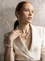 MurrinaMurano.us model wearing the blue Trace Bracelet with pale blue Murano Glass beads, peach accents, and a faceted blue glass pendant with gold-finished details. Handcrafted in Italy.