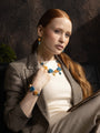 Woman wearing Edge Murano glass drop earrings with blue and orange Murano glass elements and 18KT Gold Finish over brass, handcrafted in Italy.