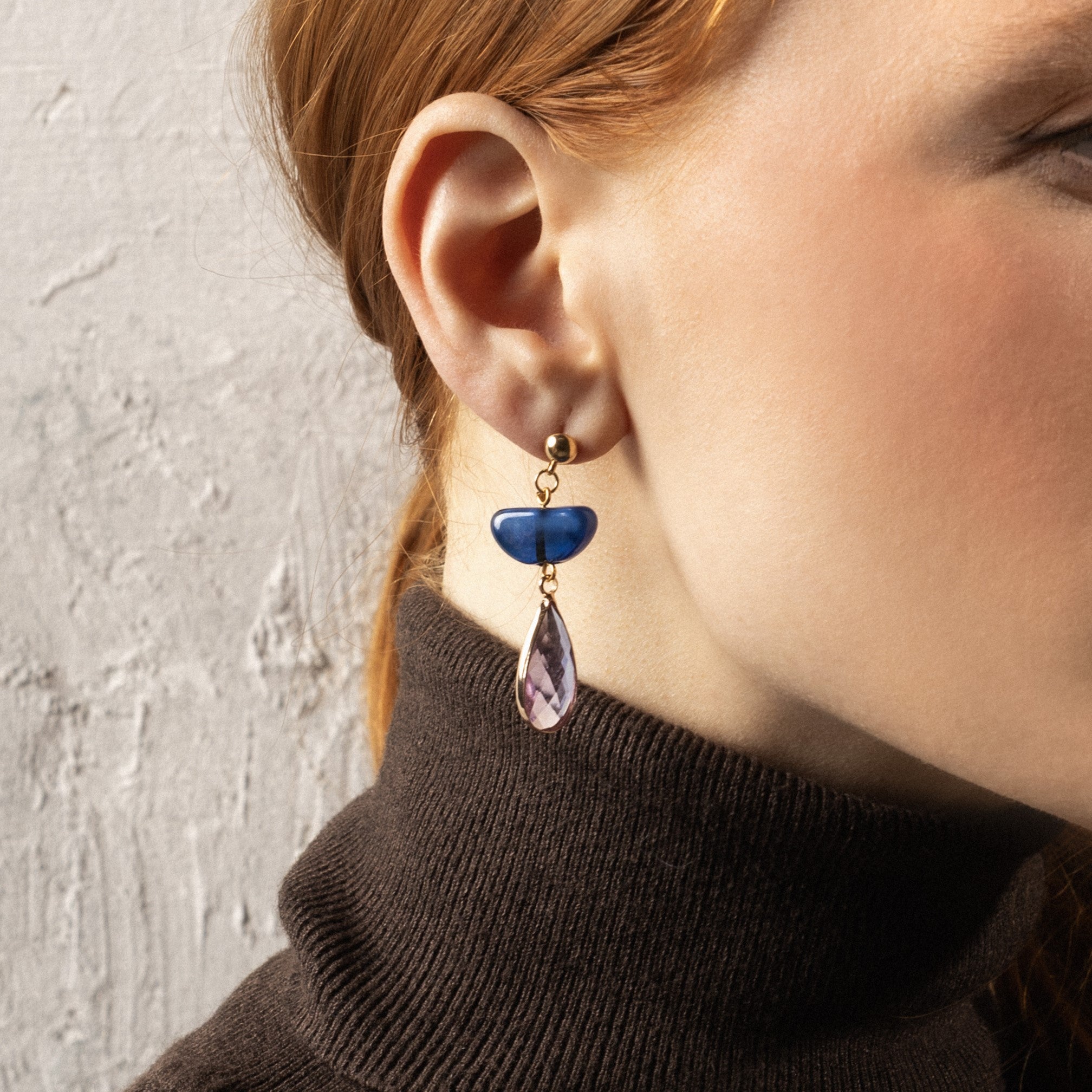 MurrinaMurano.us model wearing Core Top Drop Earrings featuring cobalt blue Murano Glass and a faceted lavender crystal drop, finished with 18KT gold-finished details. Handcrated in Italy.