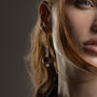 Close-up of a model wearing MurrinaMurano.us Frame drop earrings in pink Murano Glass, highlighting the delicate beaded drop and luminous sculptural glass centerpiece. Handcrafted in Italy.