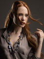 MurrinaMurano.us model wearing the blue Frame Opera Necklace, featuring luminous blue and violet Murano Glass beads with sculptural interlocking metal details. Handcrafted in Italy.