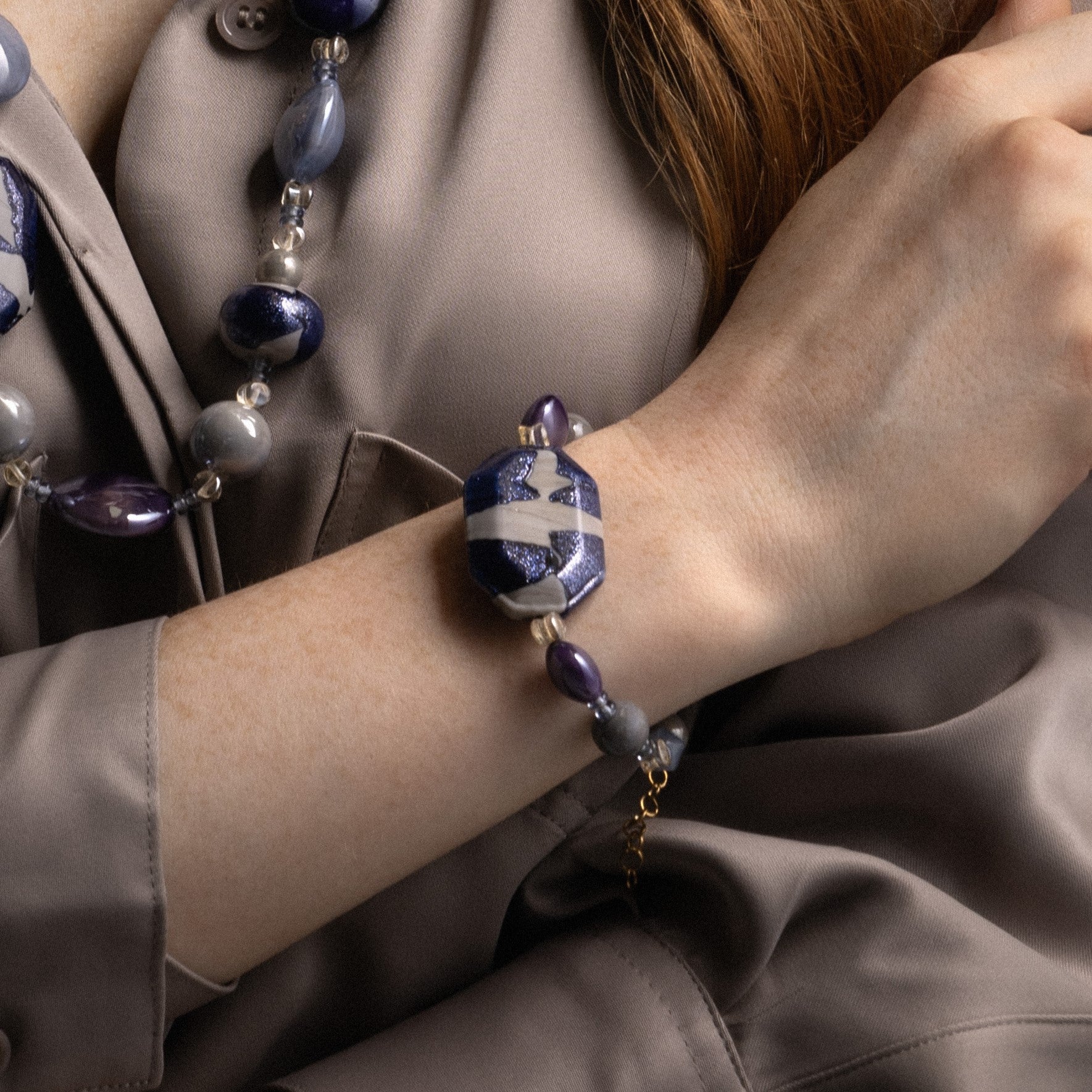 MurrinaMurano.us model wearing the blue Frame Bracelet, showcasing translucent blue Murano Glass, deep purple accents, and the sculptural blue-and-white centerpiece at the wrist. Handcrafted in Italy.