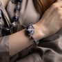 MurrinaMurano.us model wearing the blue Frame Bracelet, showcasing translucent blue Murano Glass, deep purple accents, and the sculptural blue-and-white centerpiece at the wrist. Handcrafted in Italy.