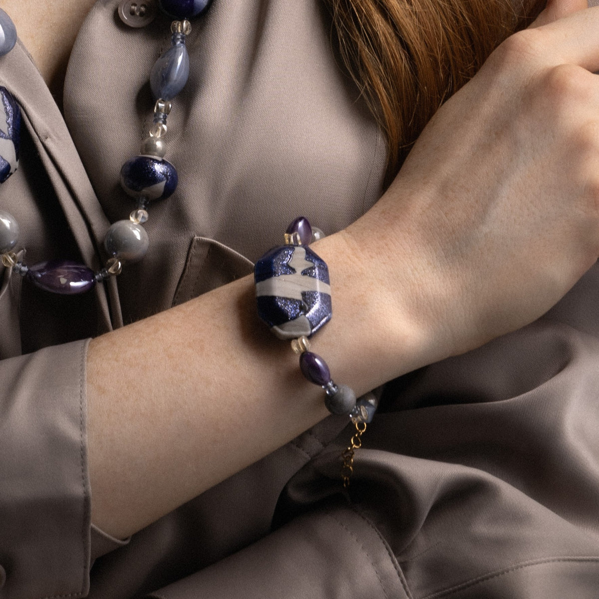 MurrinaMurano.us model wearing the blue Frame Bracelet, showcasing translucent blue Murano Glass, deep purple accents, and the sculptural blue-and-white centerpiece at the wrist. Handcrafted in Italy.