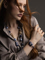 Woman wearing a Frame Bracelet in blue and purple Murano Glass, with graduated glass beads and distinctive gold-finished metal detailing. Handcrafted in Italy.
