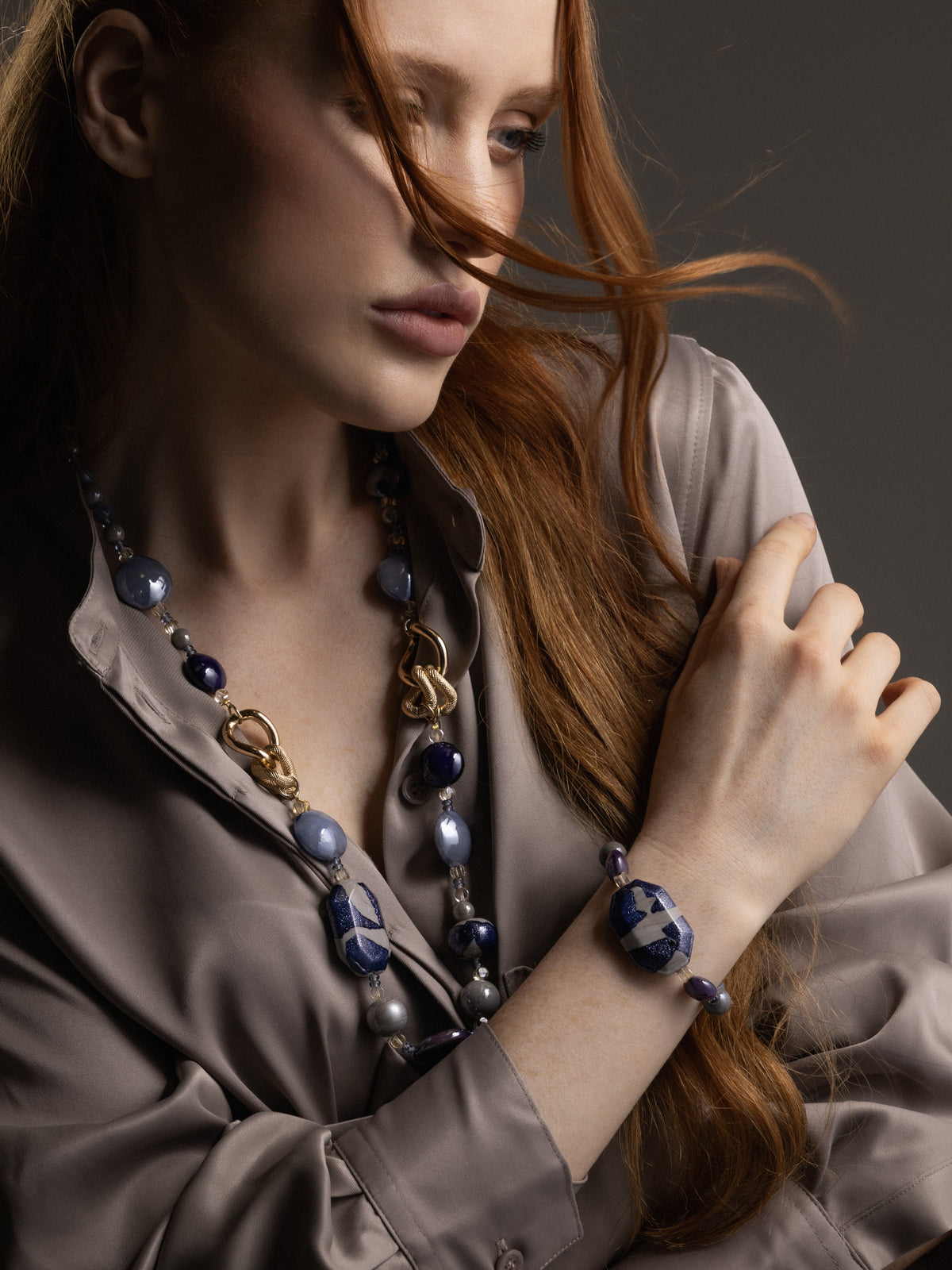 Woman wearing a Frame Bracelet in blue and purple Murano Glass, with graduated glass beads and distinctive gold-finished metal detailing. Handcrafted in Italy.