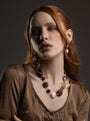 Model wearing Frame earrings in rich brown Murano Glass, with a delicate vertical arrangement of translucent beads and luminous oversized glass drops. Handcrafted in Italy.