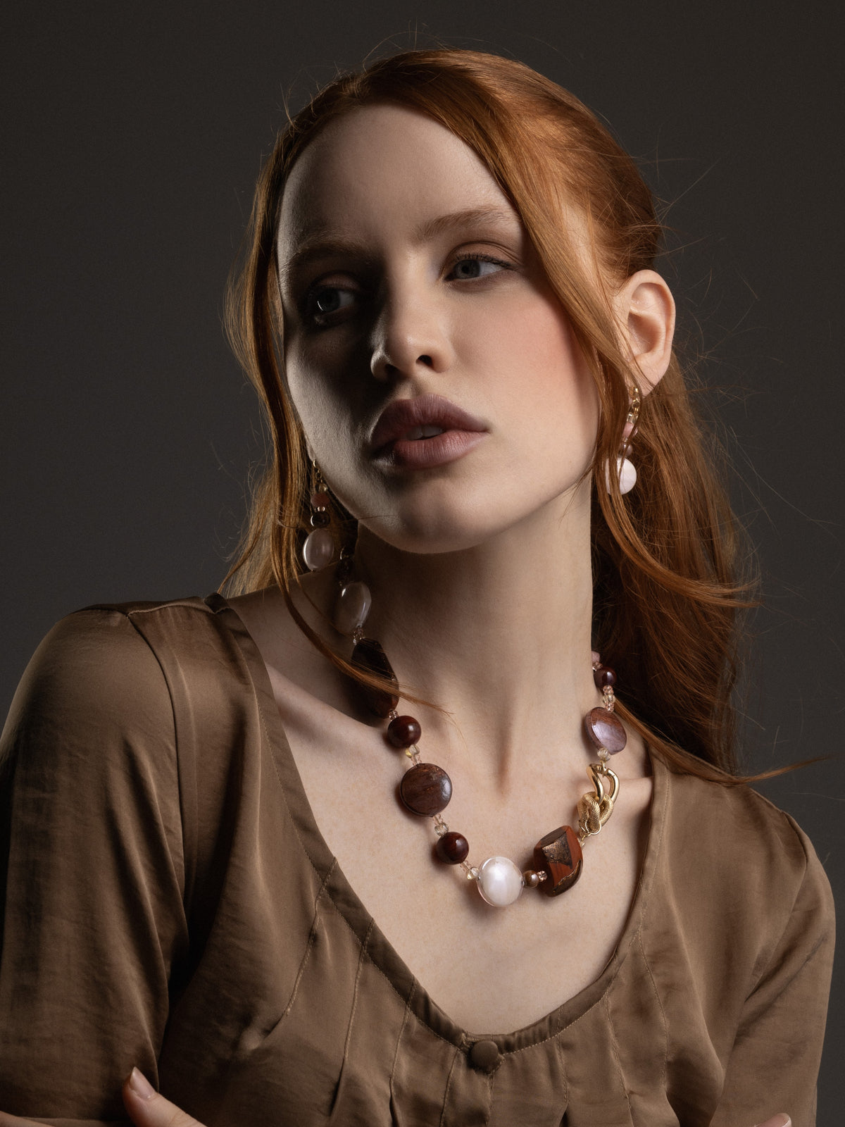 Model wearing Frame earrings in rich brown Murano Glass, with a delicate vertical arrangement of translucent beads and luminous oversized glass drops. Handcrafted in Italy.