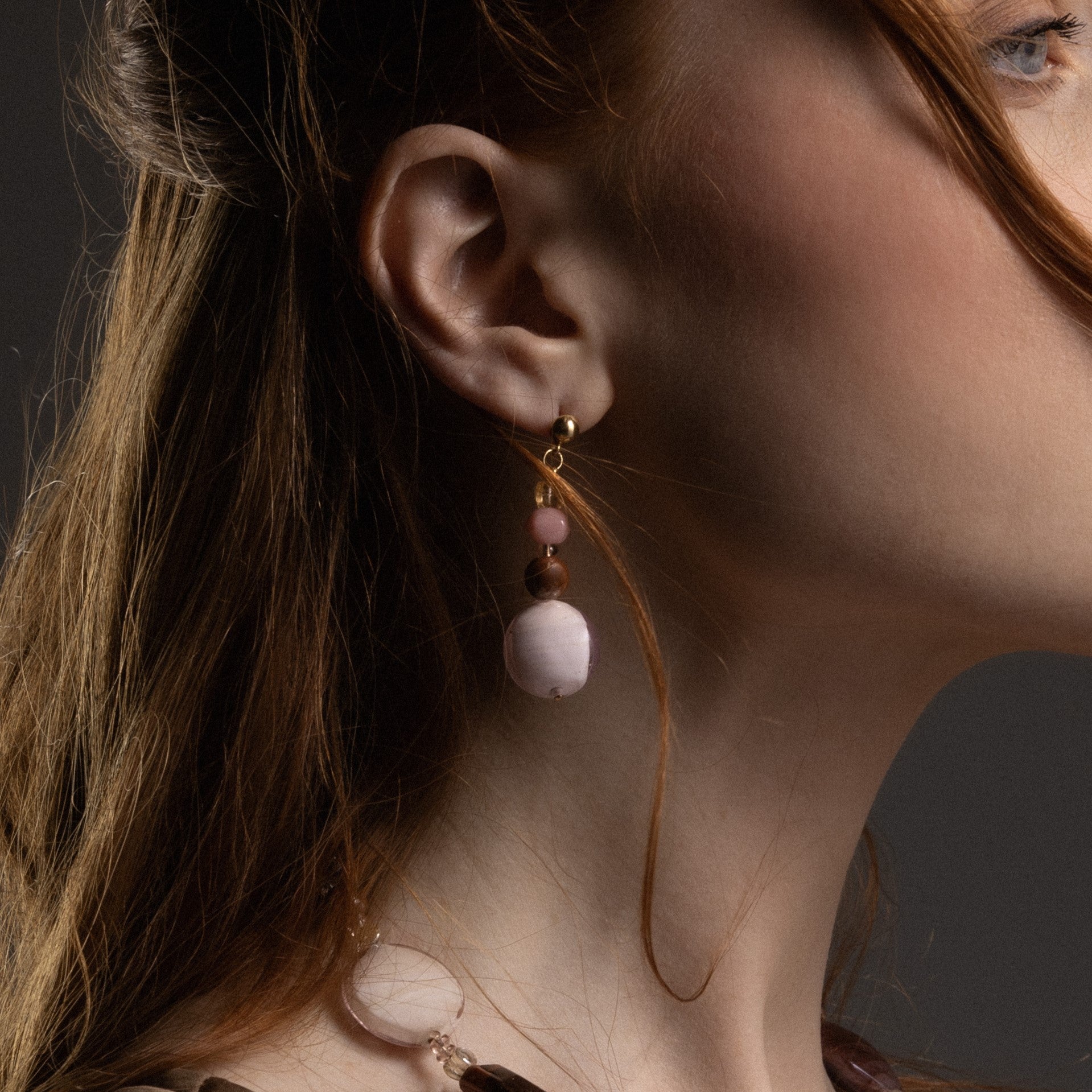 Close-up of a model wearing MurrinaMurano.us Frame drop earrings in brown Murano Glass, showcasing the layered glass beads and rounded statement drops beside the face. Handcrafted in Italy.