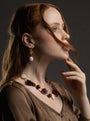 Woman wearing a Frame Choker Necklace in brown and amber Murano Glass, with distinctive interlocking metal links and textured knot details framing the neckline. Handcrafted in Italy.