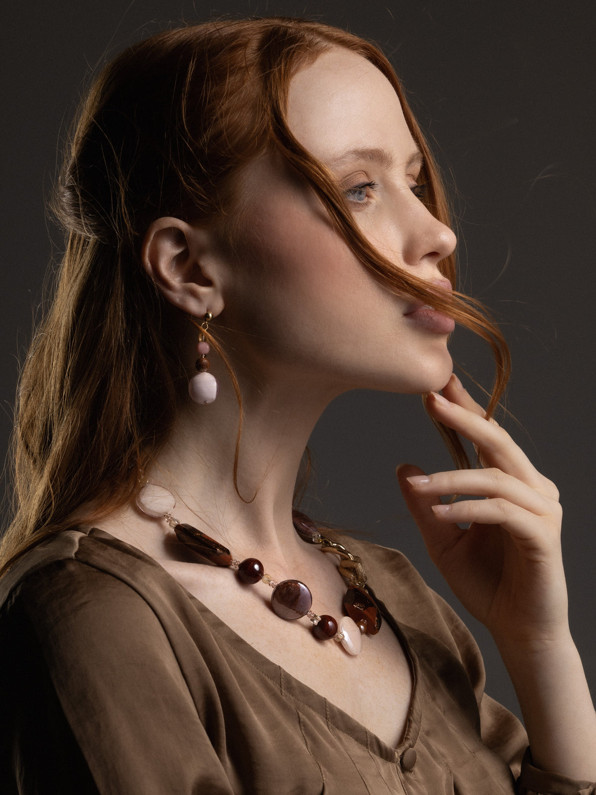 Woman wearing a Frame Choker Necklace in brown and amber Murano Glass, with distinctive interlocking metal links and textured knot details framing the neckline. Handcrafted in Italy.