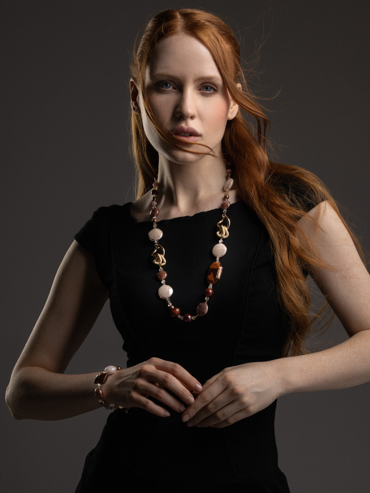 MurrinaMurano.us model wearing the brown Frame Opera Necklace, with amber and smoky Murano Glass elements arranged along an elongated silhouette and sculptural gold-finished links. Handcrafted in Italy.