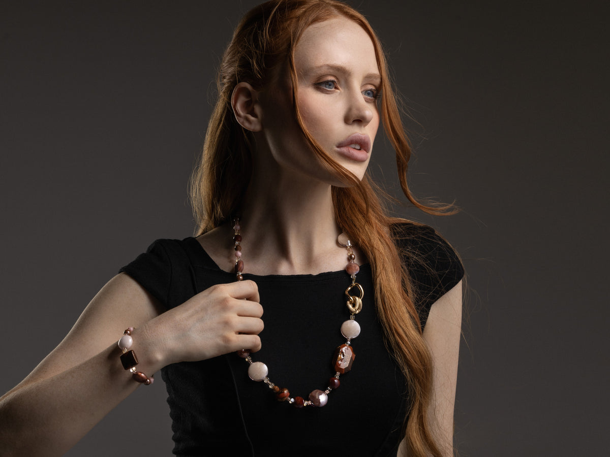 MurrinaMurano.us model wearing the brown Easy Bracelet, featuring translucent amber and cream Murano Glass beads, warm brown accents, and a geometric glass centerpiece with gold-finished details. Handcrafted in Italy.