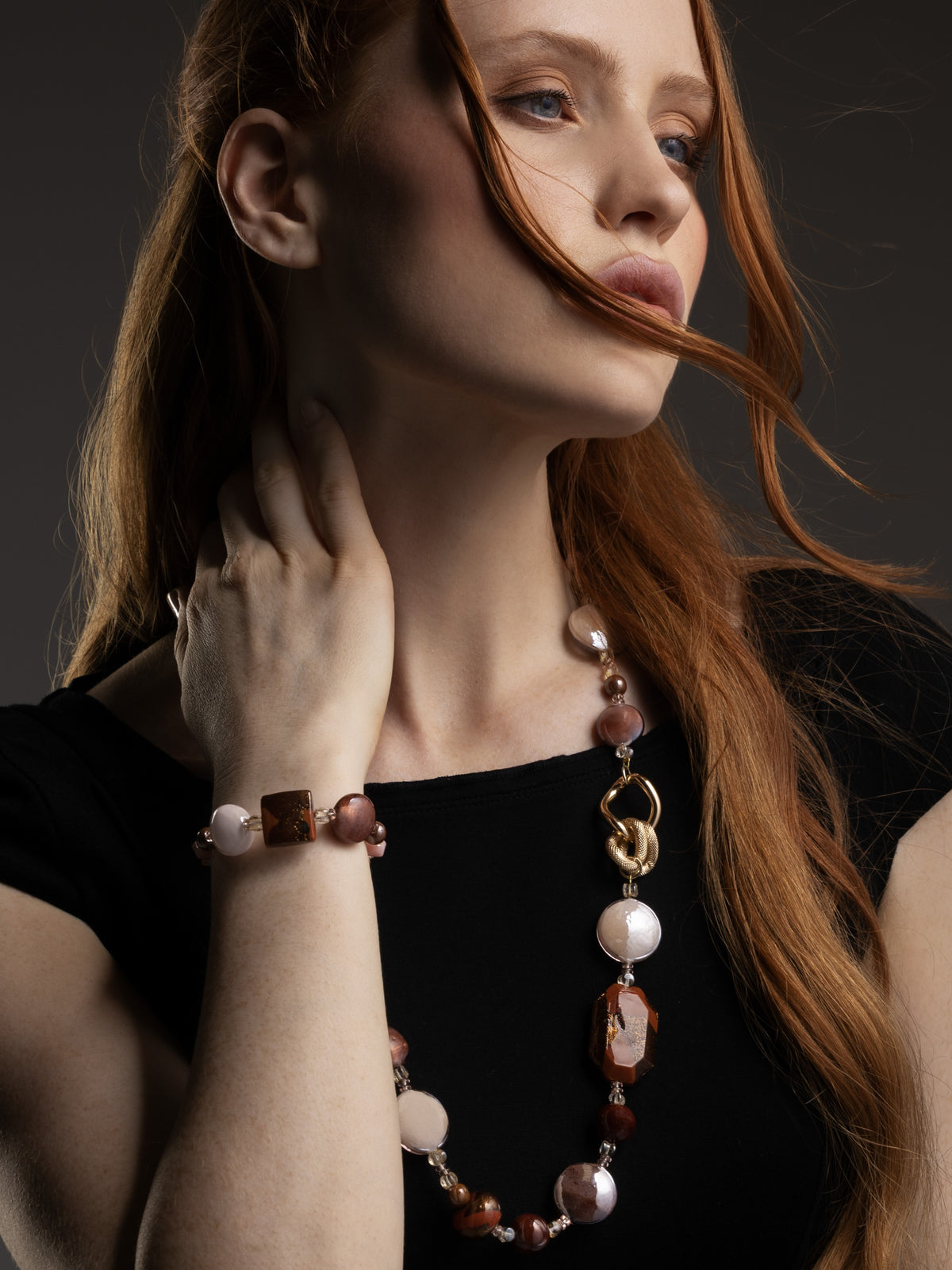 Woman wearing a brown Easy Murano Glass Bracelet with amber and cream glass elements, styled with an adjustable gold-finished chain. Handcrafted in Italy.