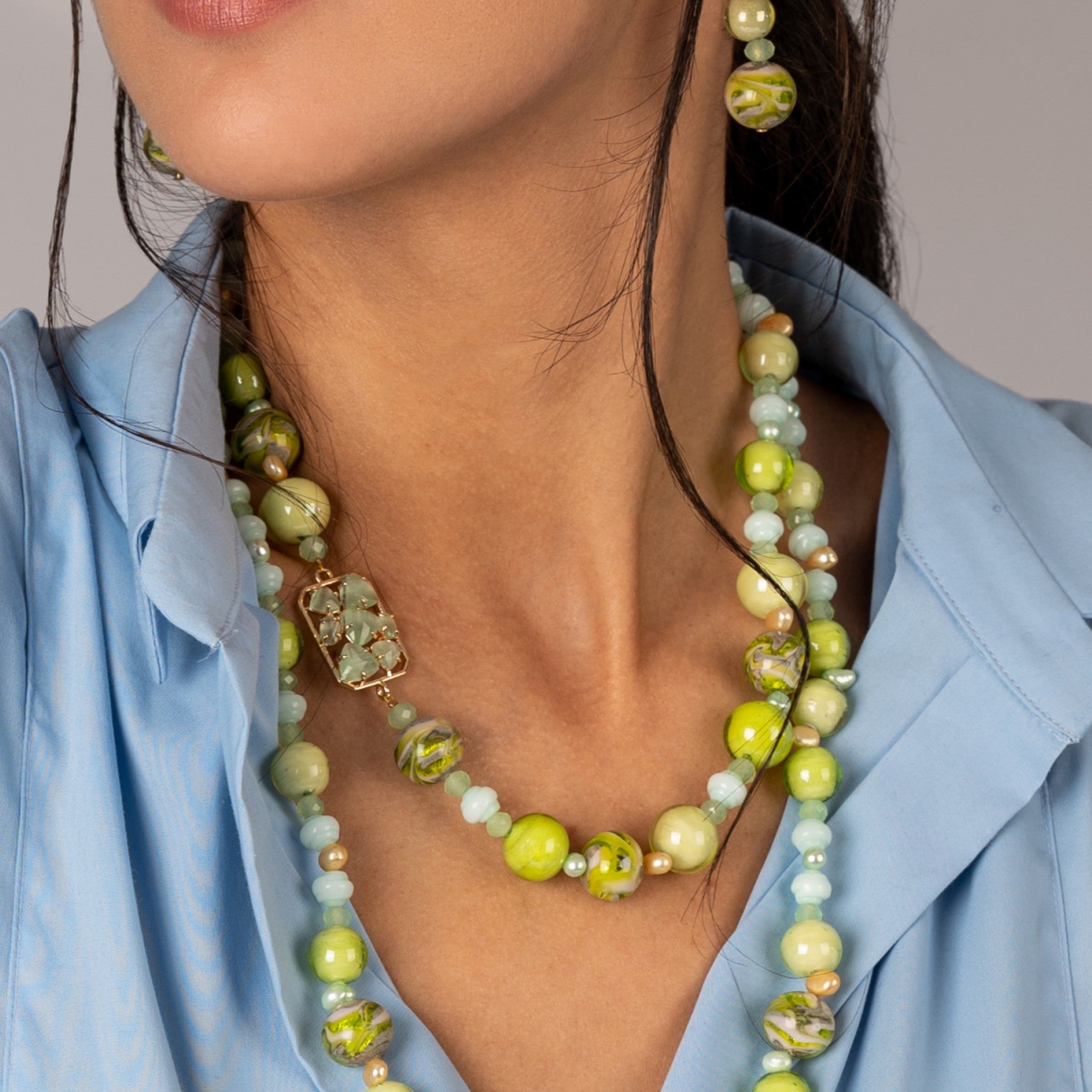 Model wearing MURRINAMURANO Venezia necklace from the Zefiro Collection, handcrafted in Original Murano glass, 18KT Gold Finish or Rhodium finish, over Brass. Made in Italy – murrinamurano.us