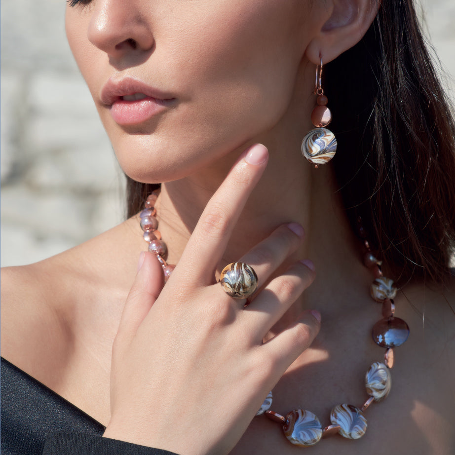 Model wearing MURRINAMURANO Venezia Necklace, Earrings and ring from the Atena Collection, handcrafted in Original Murano glass,  with 18KT Gold Finish over Stainless Steel, Made in Italy, Atena Collection