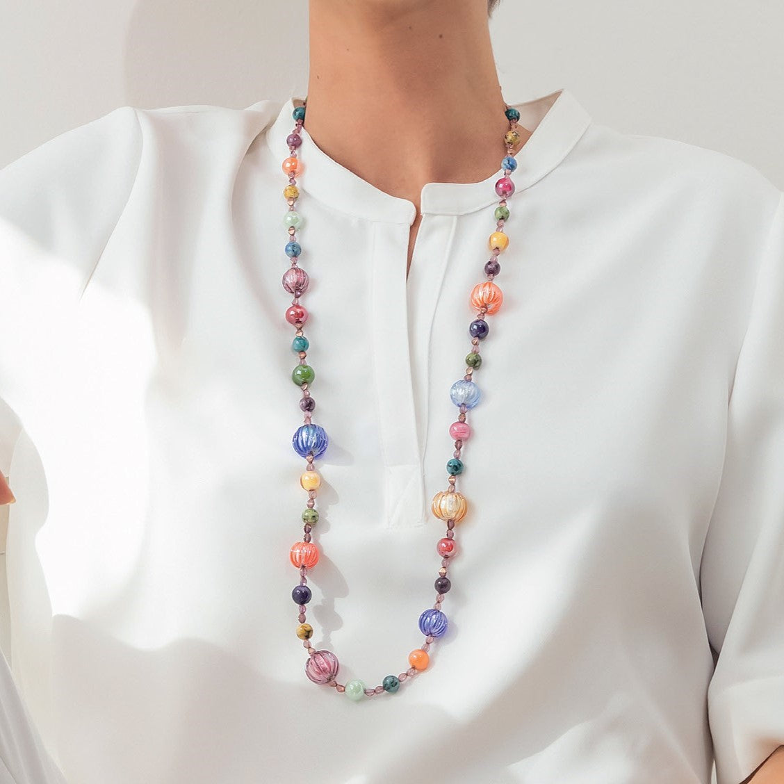 Model wearing MURRINAMURANO Venezia necklace from the Gea Collection, handcrafted in Original Murano glass,  with 18KT Gold Finish over Stainless Steel, Made in Italy – Gea Collection. murrinamurano.us